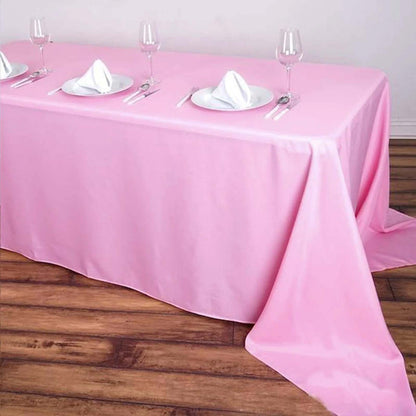 Pink tablecloth draped elegantly over a dining table with plates and glasses.