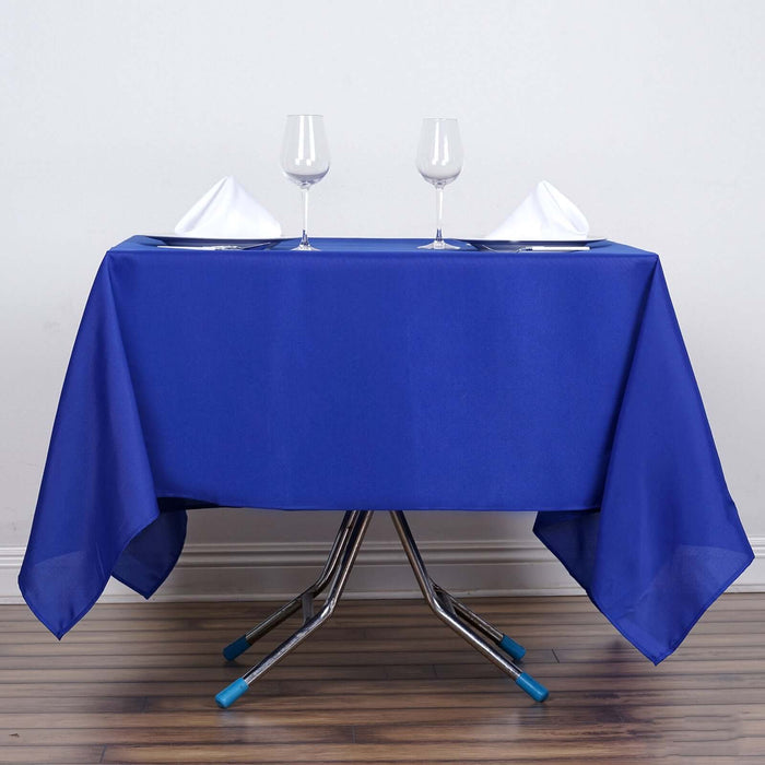 Blue tablecloth with wine glasses and folded napkins on a table.