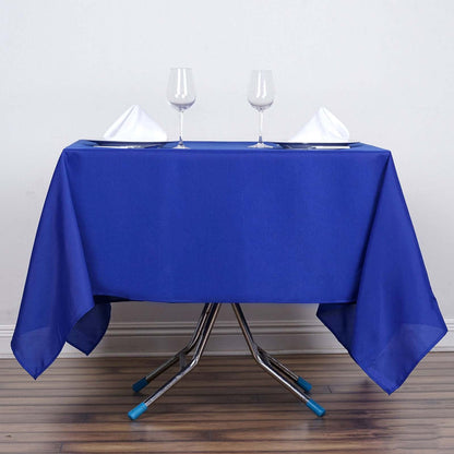 Blue tablecloth with wine glasses and folded napkins on a table.