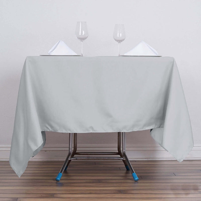 Gray tablecloth draped over a table with glasses and napkins.