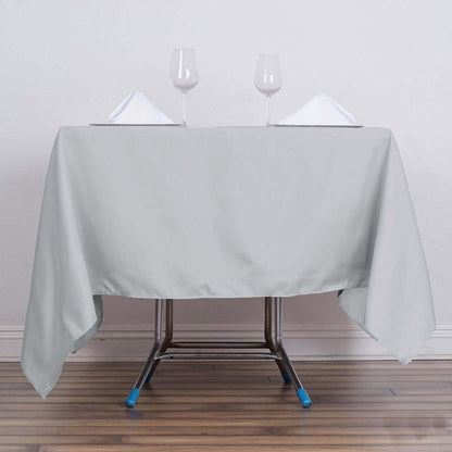 Gray tablecloth draped over a table with glasses and napkins.