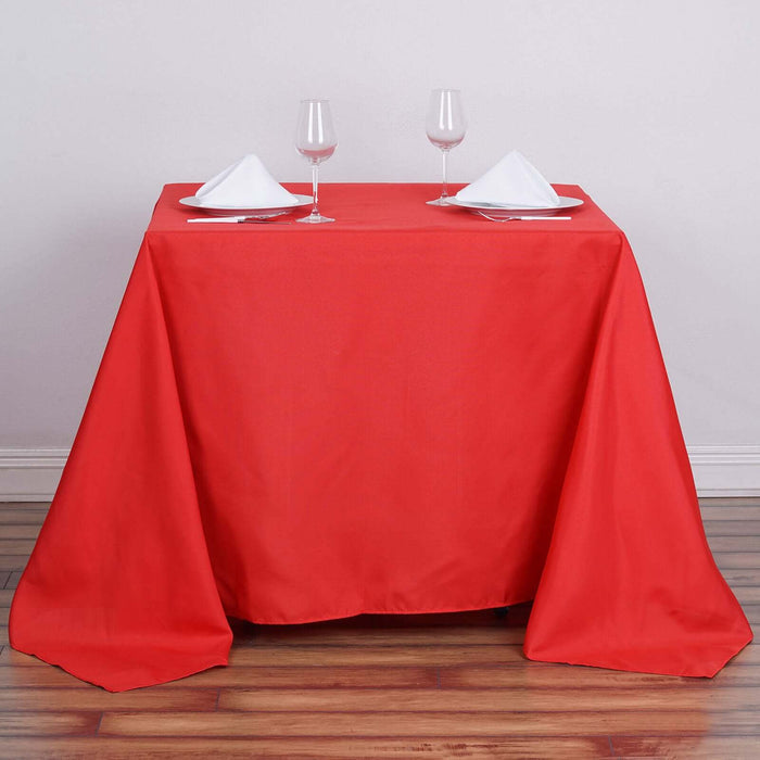 Red tablecloth elegantly draped over a dining table set for two.