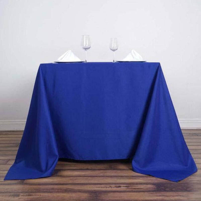 Blue tablecloth draped over a table with wine glasses and folded napkins.