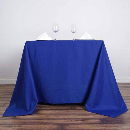 Blue tablecloth draped over a table with wine glasses and folded napkins.