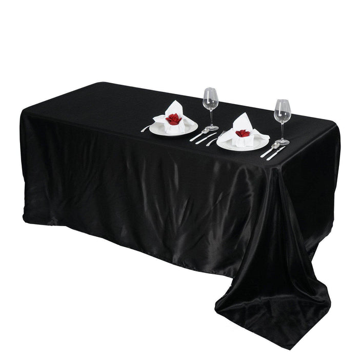 Elegant black tablecloth with dining setup, plates, and glasses.