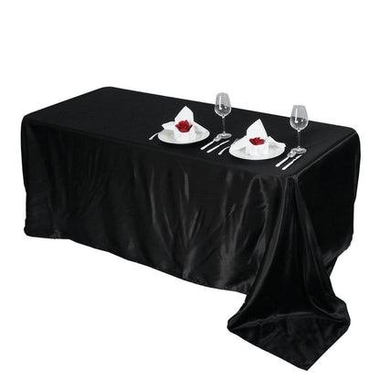Elegant black tablecloth with dining setup, plates, and glasses.