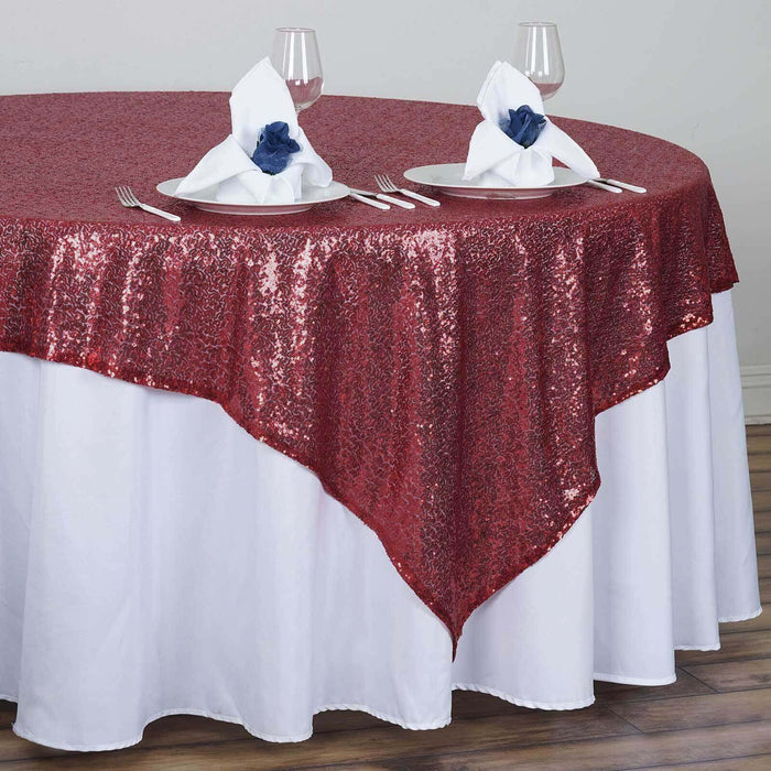 Red sequin tablecloth draped over a white table with elegant napkins.