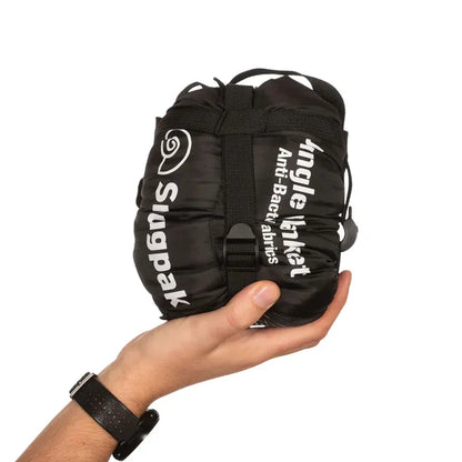Snugpak Jungle Blanket in black packed in its compression stuffsack and held in someones hand on a white background